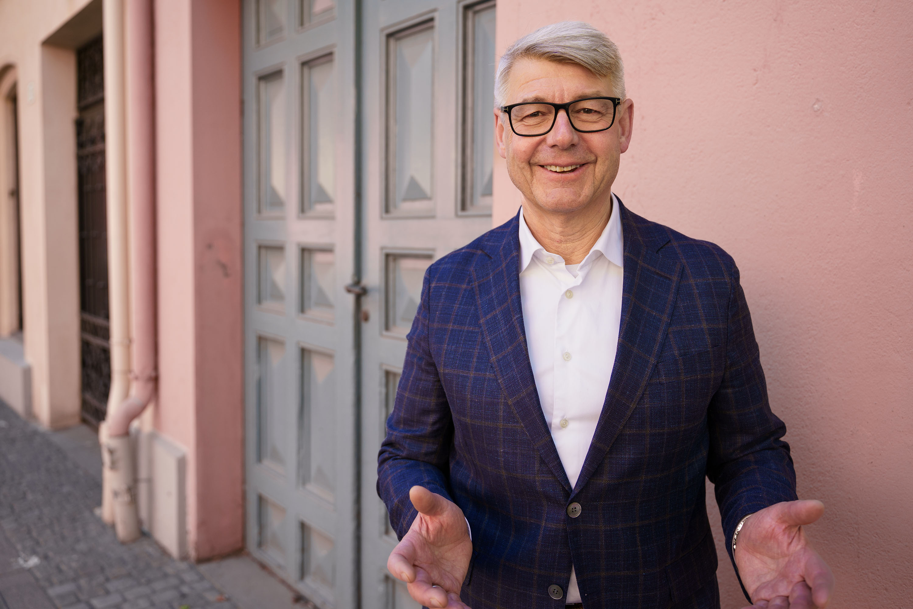 Foto: Morten Andreas Meyer smiler foran en rosa husvegg og en grønn dør.